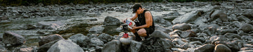 Backcountry hiker preparing a Mountain House pouch by a creek